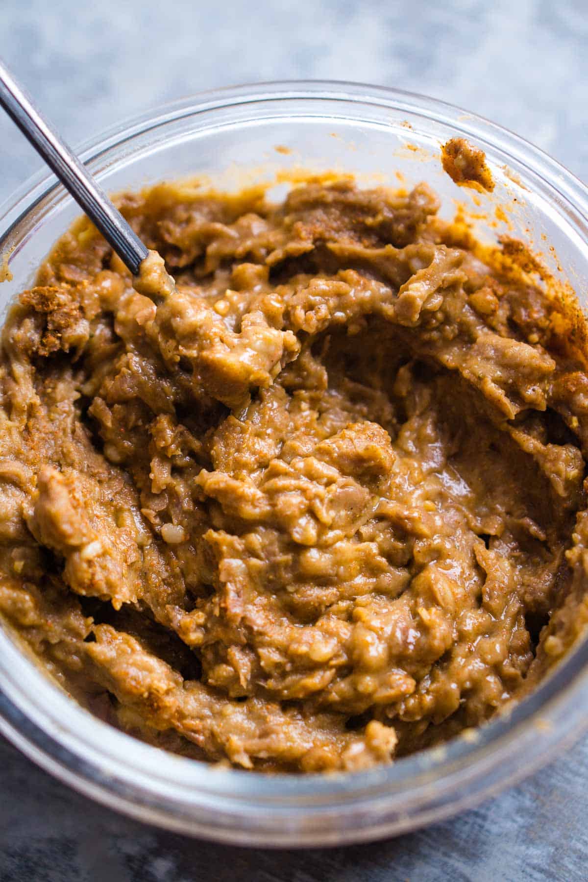 refried beans are stirred in glass container