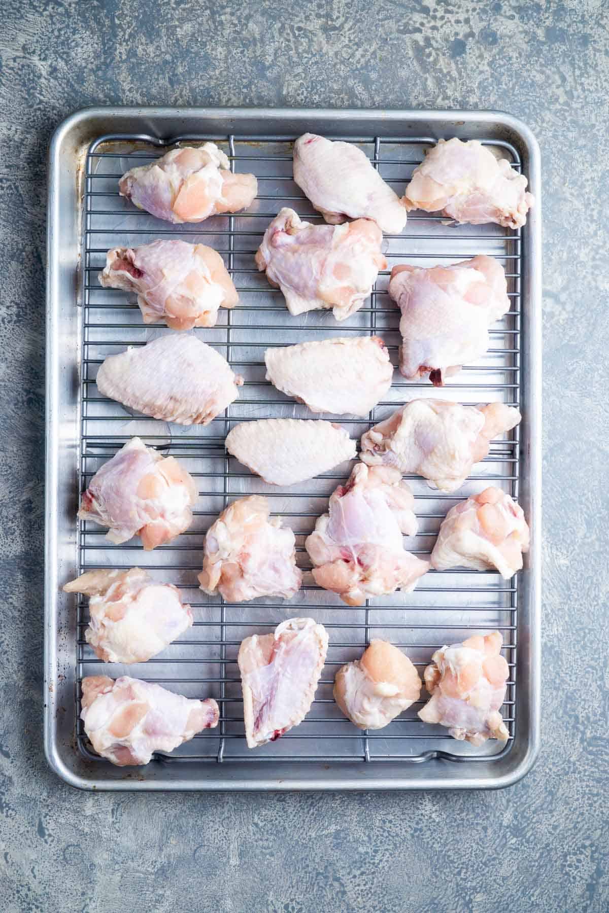 uncooked chicken wings on baking grid over baking sheet