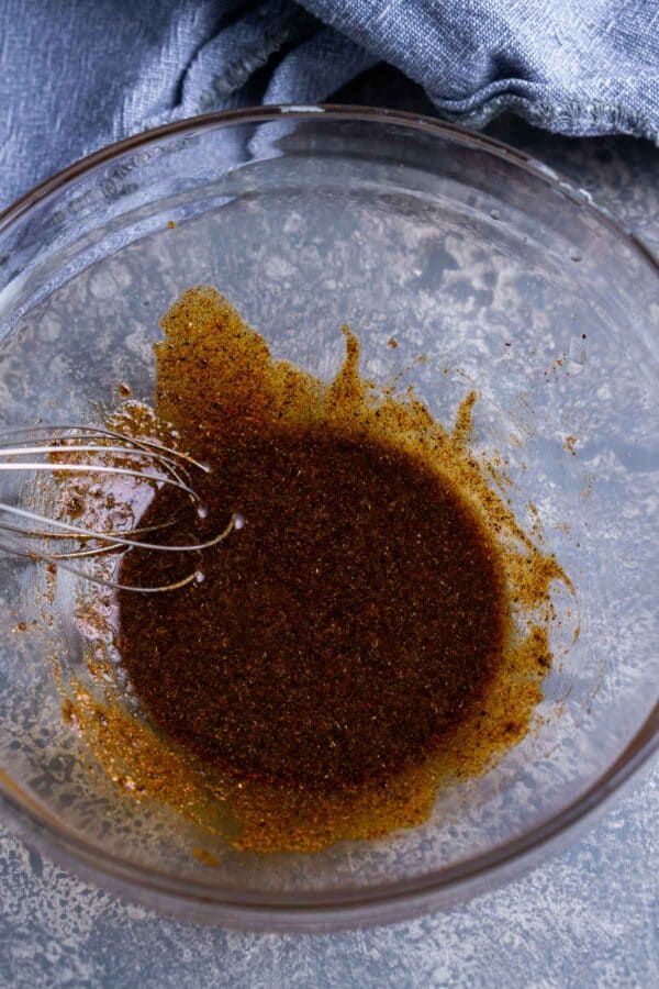 seasoning for baked chicken wings being whisked in glass bowl
