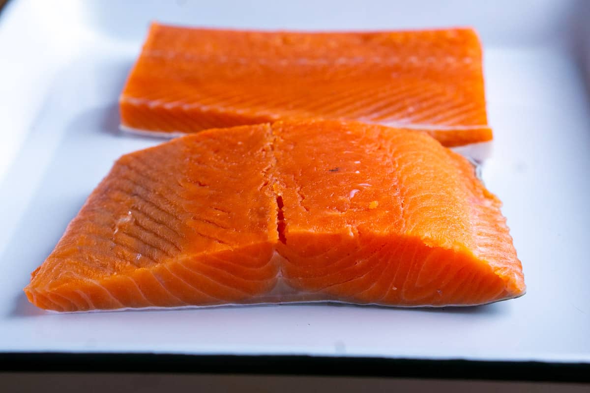 uncooked salmon fillet on white baking sheet