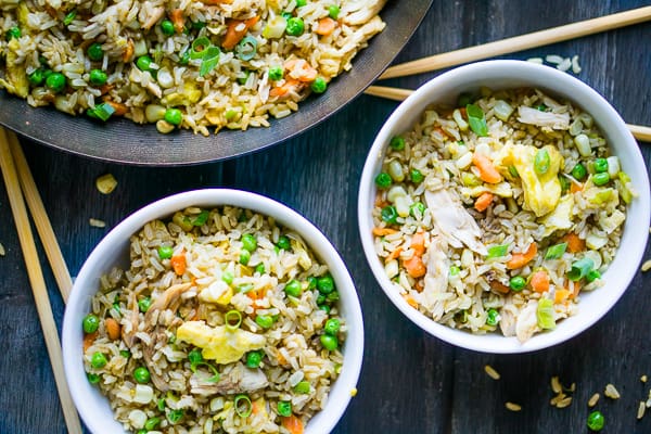 chicken fried rice in white bowl with chopsticks on grey background
