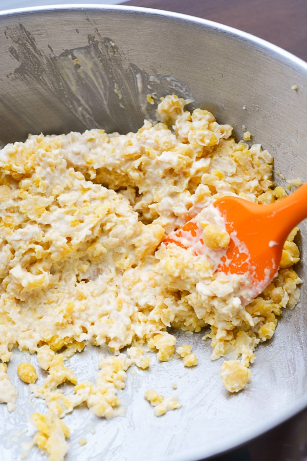 chickpea salad being mixed by orange spatula in a stainless bowl