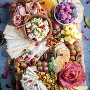 Christmas charcuterie board with cured meats, cheeses, fruit, crackers, nuts, jam, and holiday garnishes