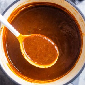 A pot of thick red sauce with a white spoon resting inside.