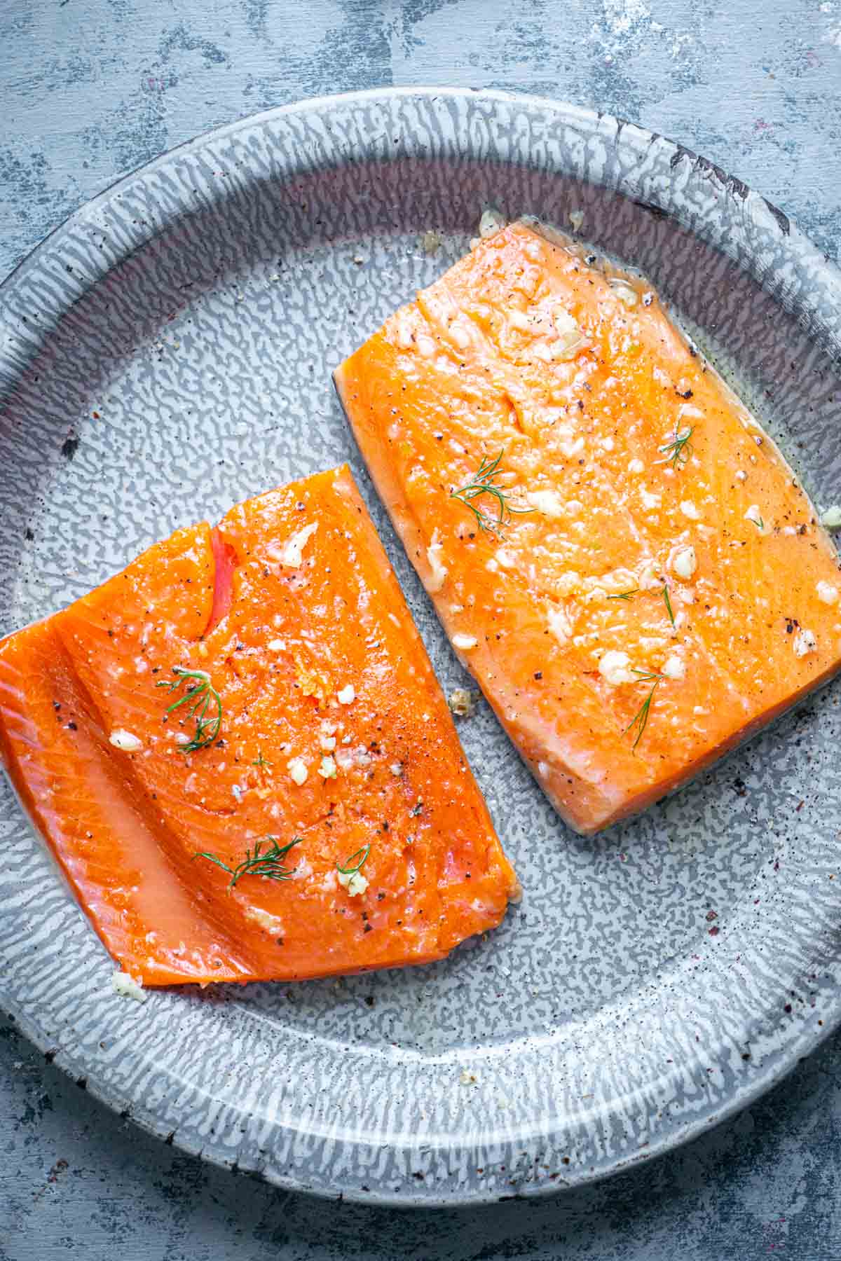 raw salmon fillets on gray plate
