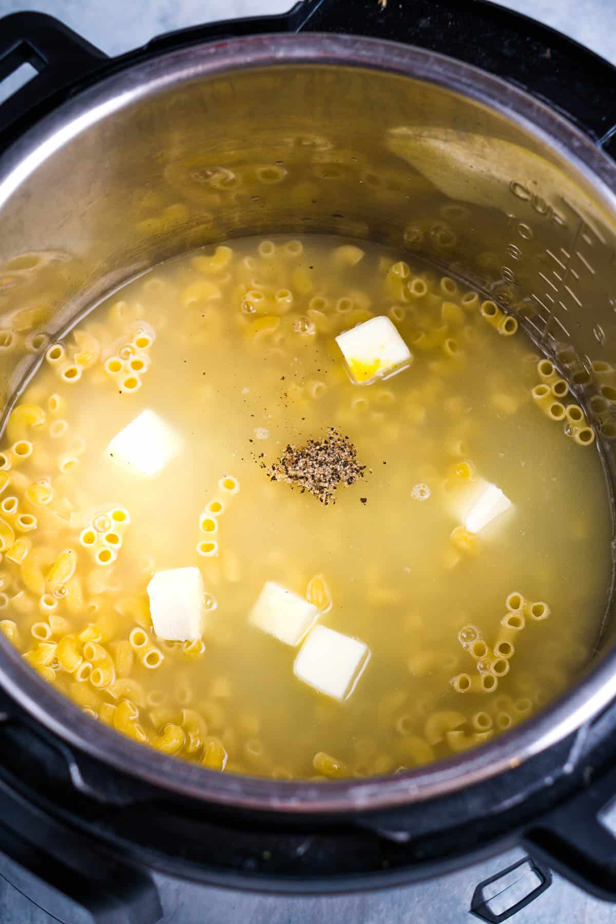 uncooked macaroni noodles, broth, butter, and black pepper in Instant Pot