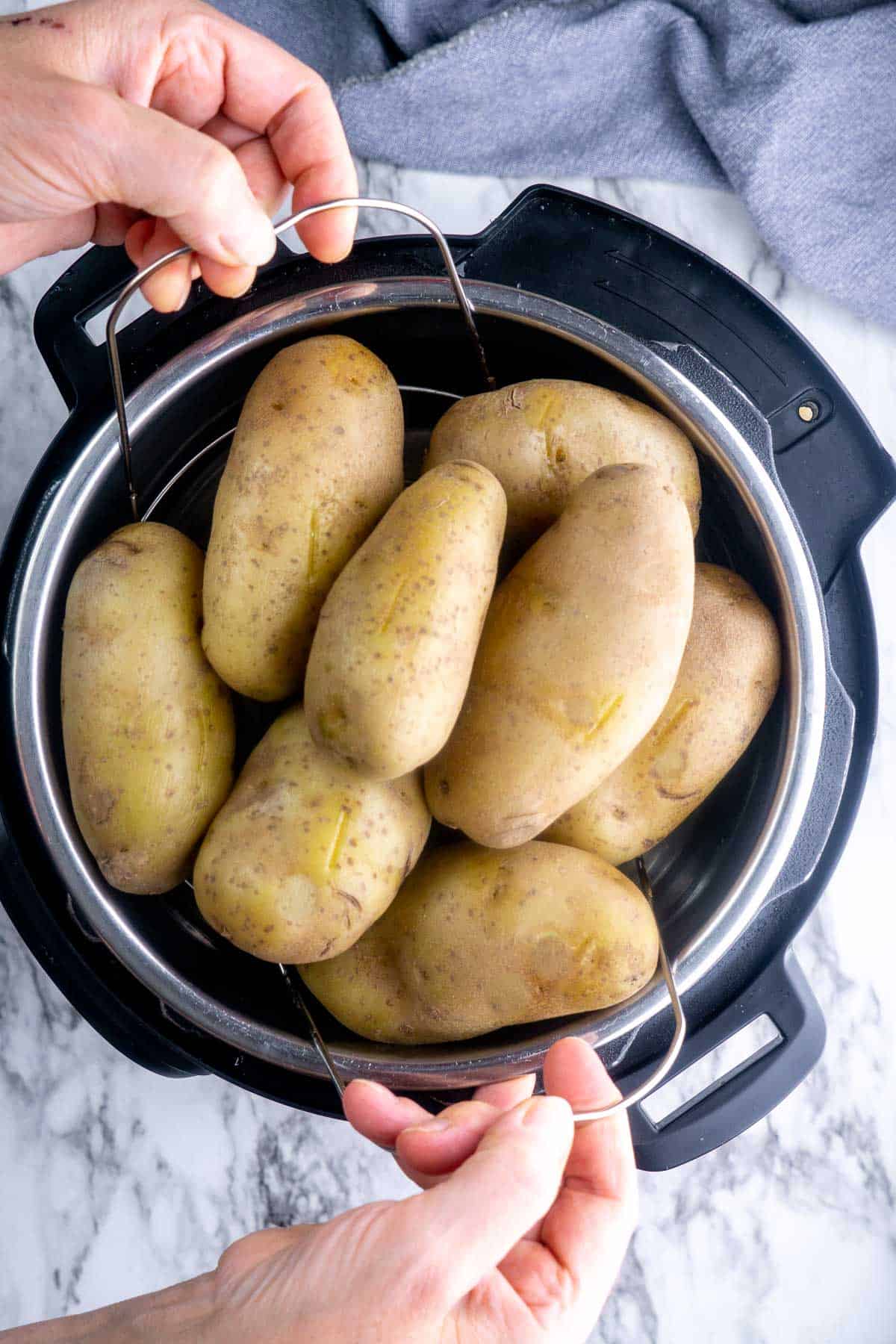 whole potatoes in instant pot being lifted with trivet