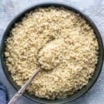 cooked quinoa in ceramic serving bowl with serving spoon