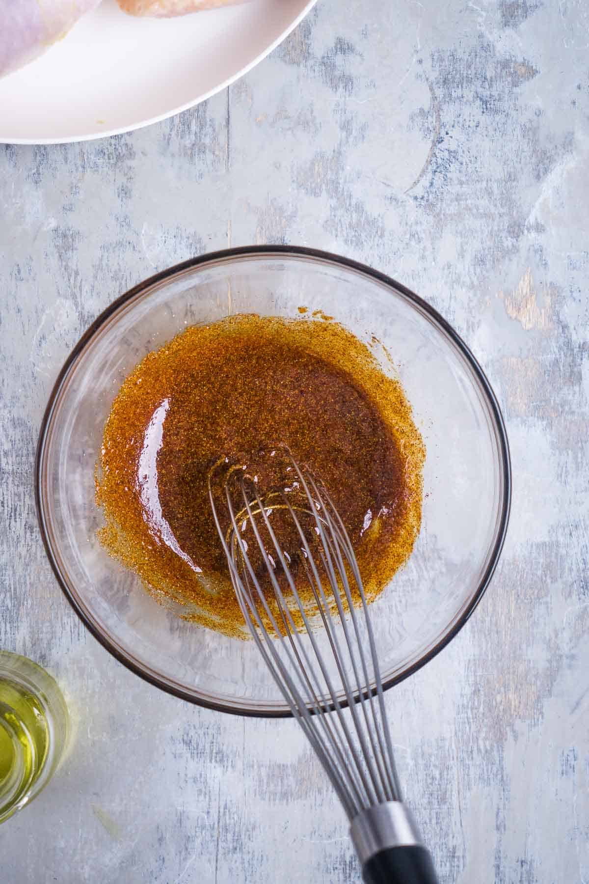 Chicken seasoning is whisked in glass mixing bowl