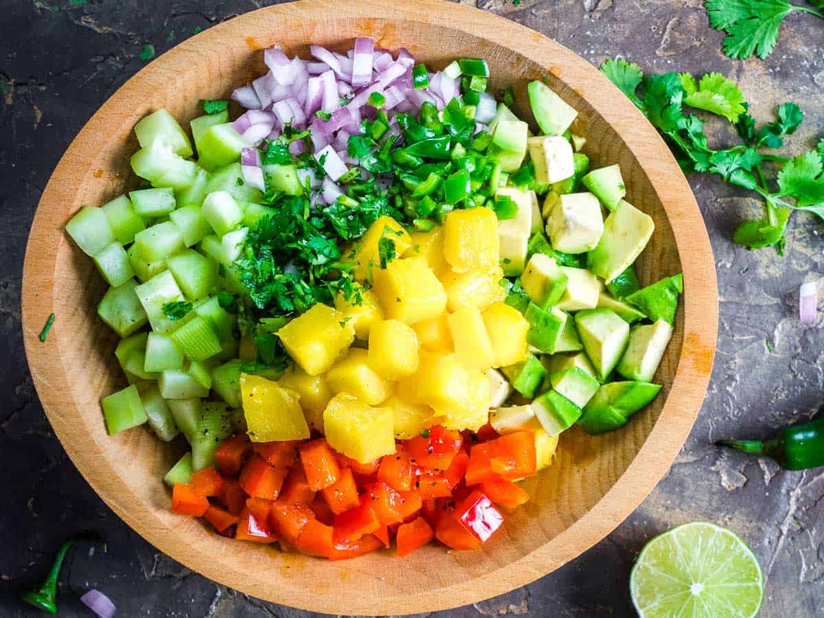 mango salsa in wood bowl next to lime half