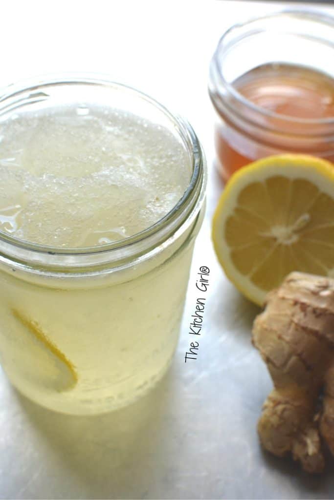 sore throat relief slushie in mason jar next to honey, lemon, and ginger root