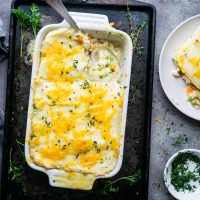 Shepherd's pie in white baking dish with section cut out by serving spoon