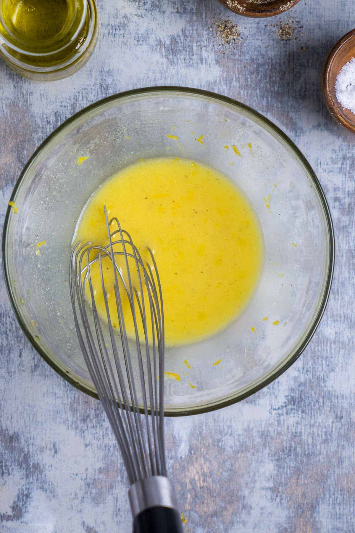 lemon dressing ingredients are whisked in glass bowl