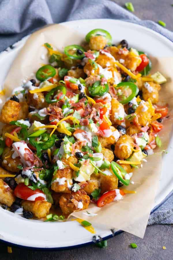 Totchos tater tot nachos on parchment covered white platter with blue linen