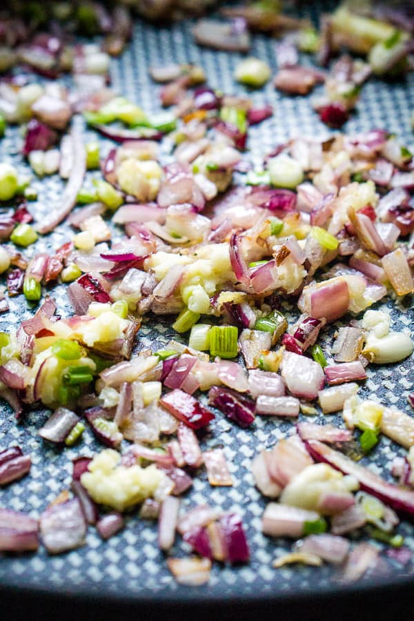 red onions and celery being sauteed in skillet