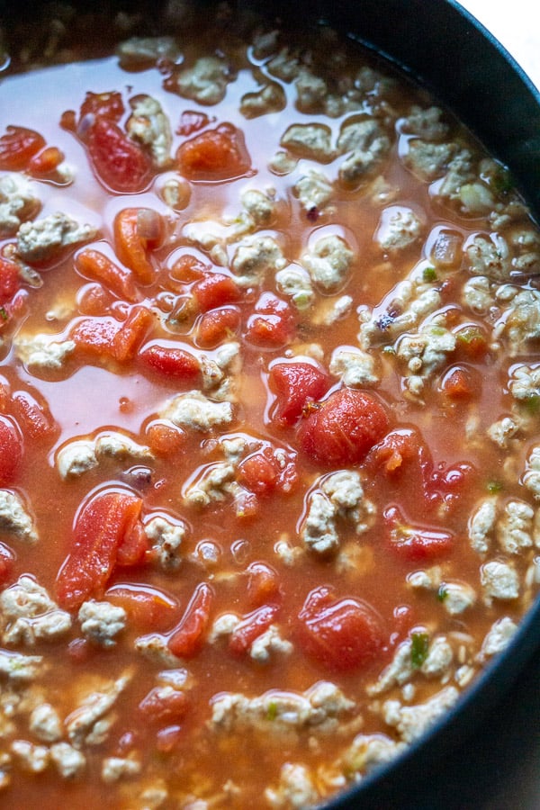 turkey taco meat in skillet with tomatoes and chicken broth