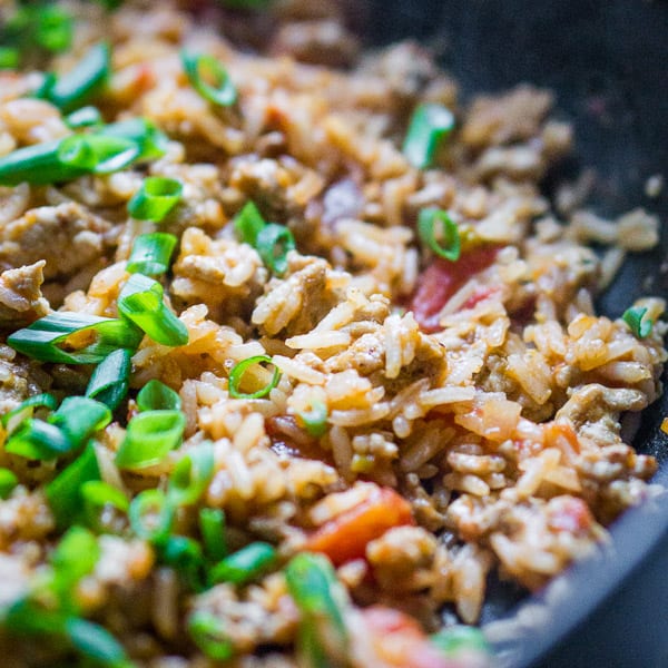 turkey taco meat and rice in skillet with tomatoes and green onions
