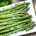 asparagus with Parmesan and chopped parsley garnish on white serving plate