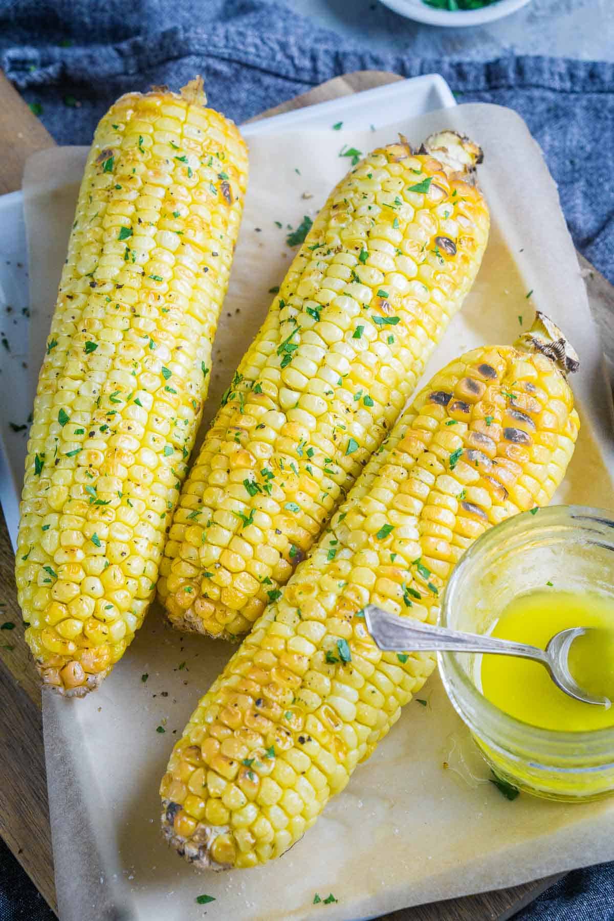 air fryer corn on the cob and jar of melted butter on serving platter