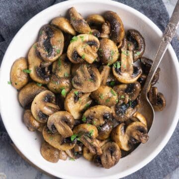 air fryer mushrooms in white bowl with serving spoon