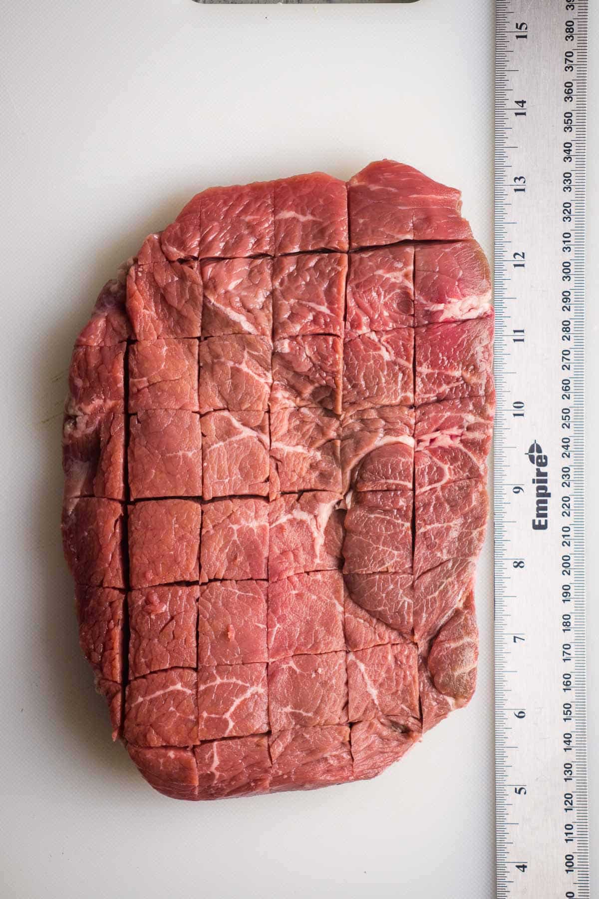 steak with scored surface next to ruler