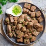 Air fryer steak bites on gray serving plate with garlic butter sauce