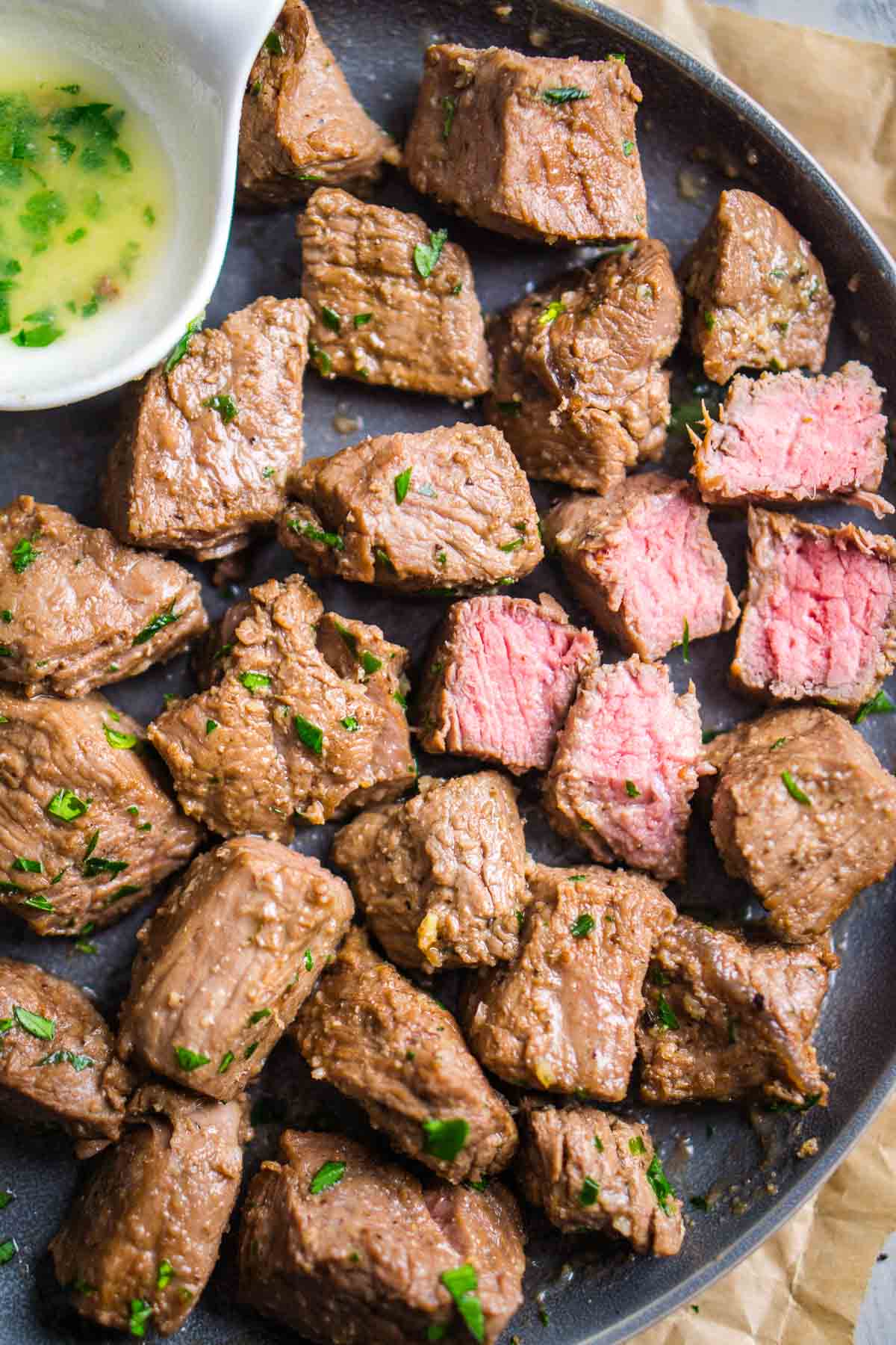 Air fryer steak bites on gray serving plate with garlic butter sauce