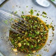 wire whisk and dressing ingredients in glass mixing bowl