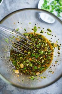 wire whisk and dressing ingredients in glass mixing bowl