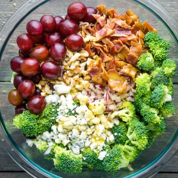 Broccoli salad ingredients with broccoli salad dressing in glass bowl on gray wood surface