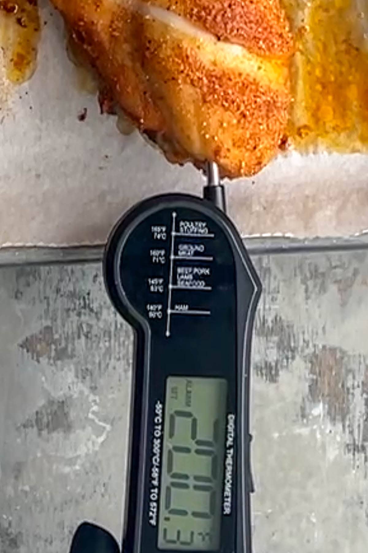 A meat thermometer inserted into a seasoned crispy baked chicken leg displays an internal temperature of 200&deg;F.