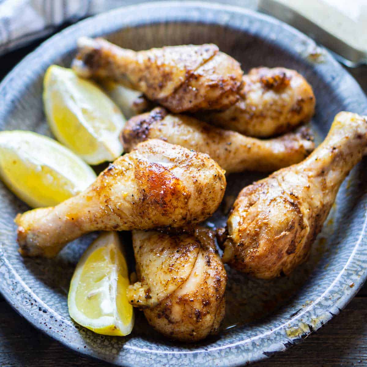 crispy and juicy chicken legs on blue serving platter with lemon wedges