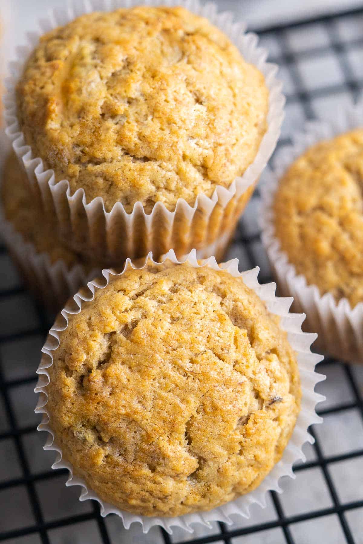 baked banana bread muffins in cupcake liners stacked on black cooling rack