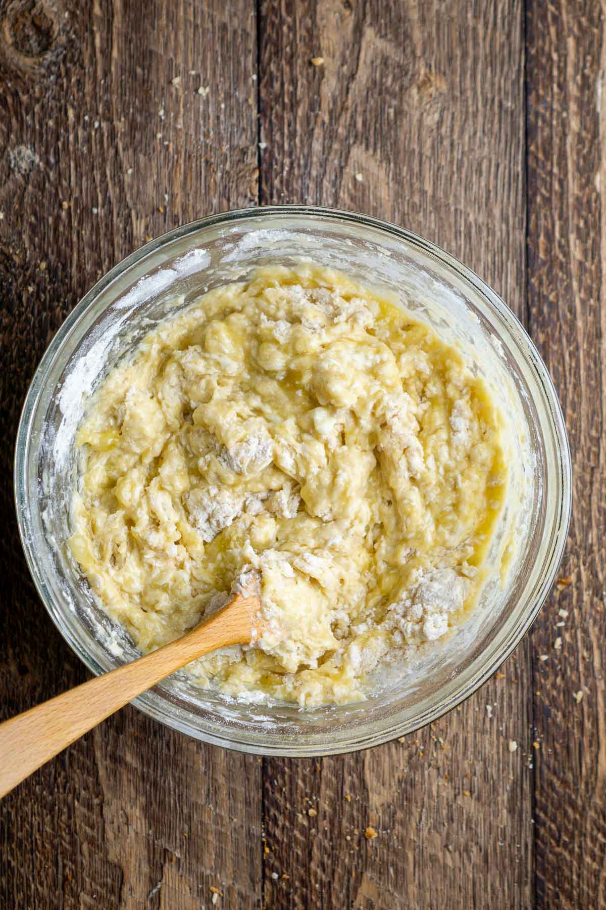 Partially mixed yellow batter in a glass bowl.
