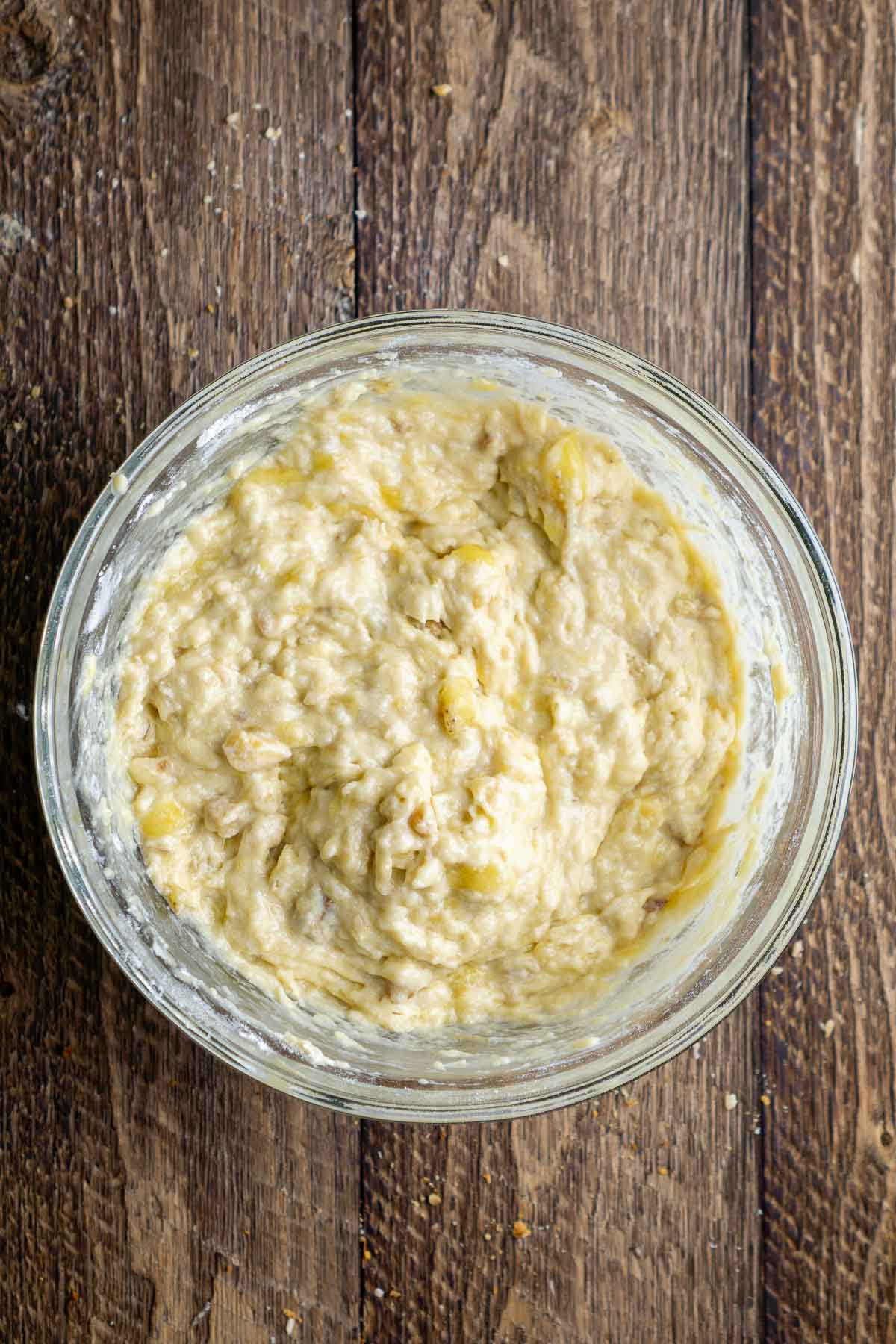 Mixed banana bread batter in a glass bowl.
