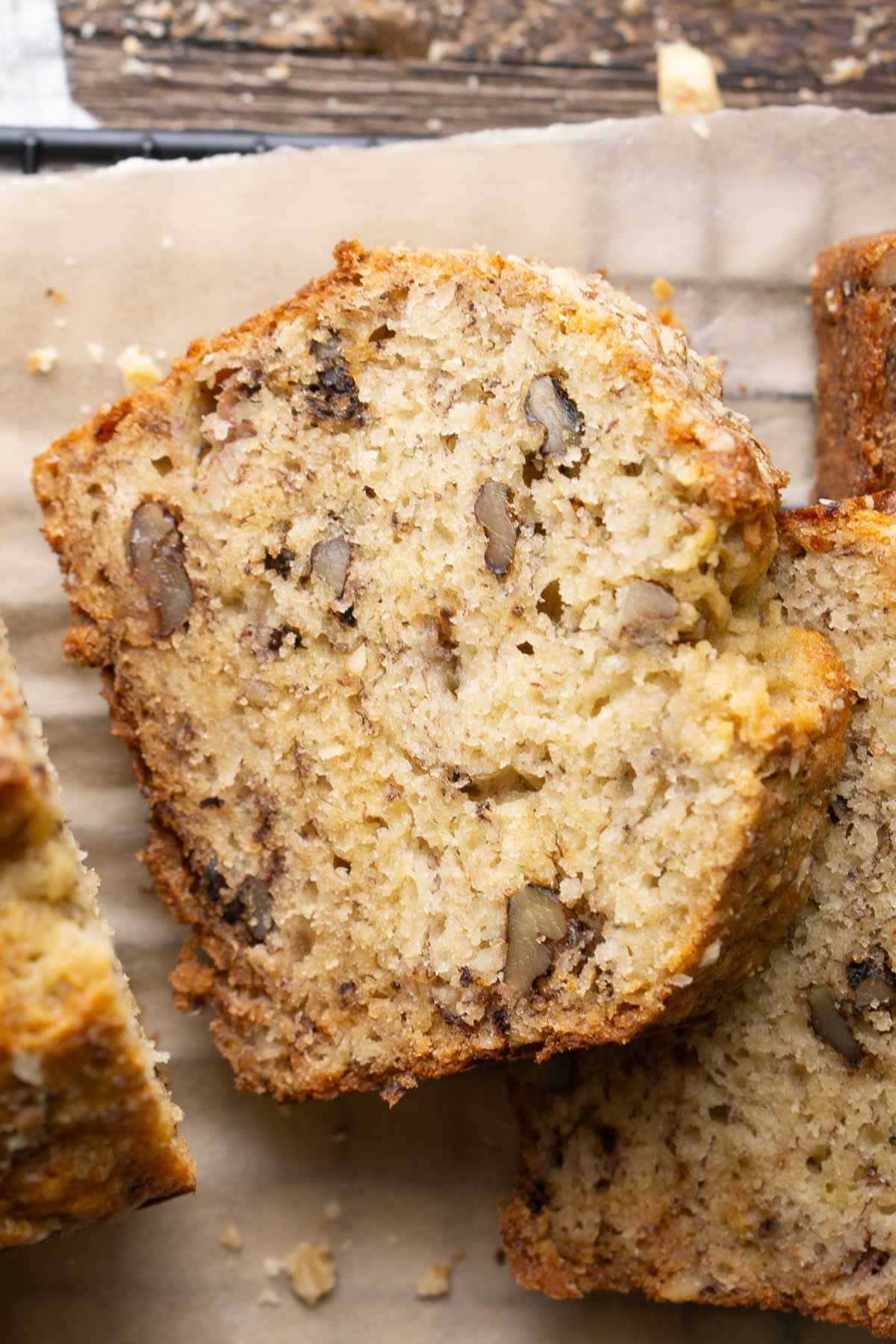 Close-up of delicious banana nut bread with visible walnut pieces, resting on parchment paper.
