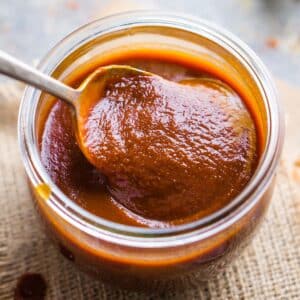 spoon lifts BBQ sauce from glass jar