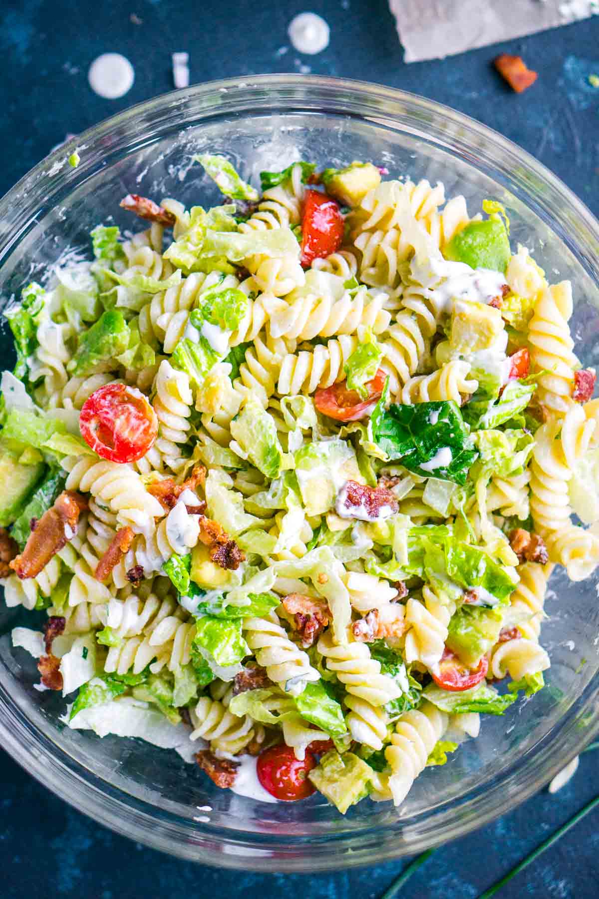 A glass bowl filled with tossed blt pasta salad.