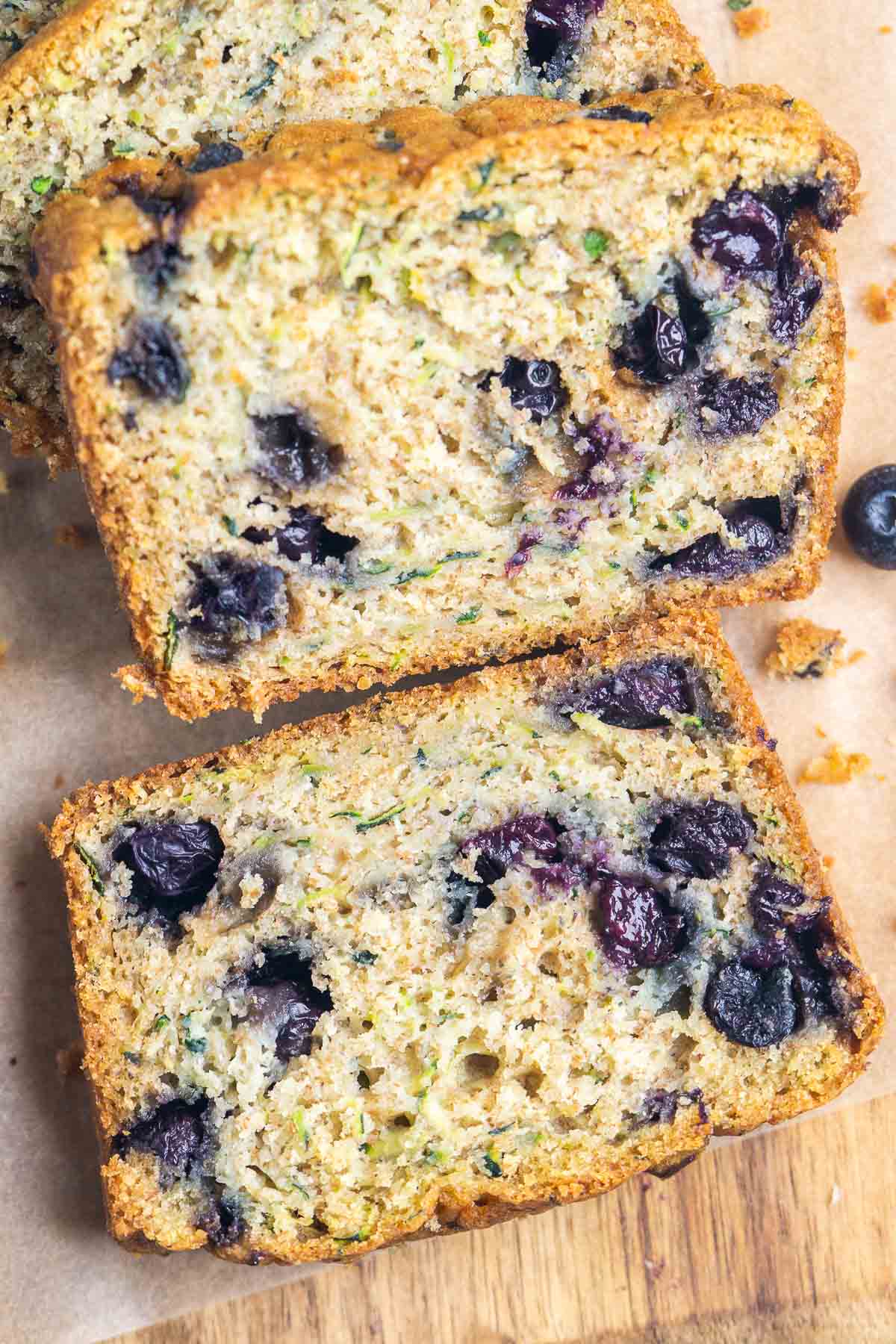 Close-up of sliced blueberry zucchini bread showing visible blueberries and bits of shredded zucchini in the moist, golden-brown crumb.