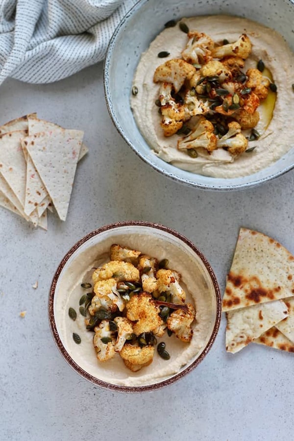 Roasted Cauliflower Hummus Bowls in ceramic bowls next to pita bread