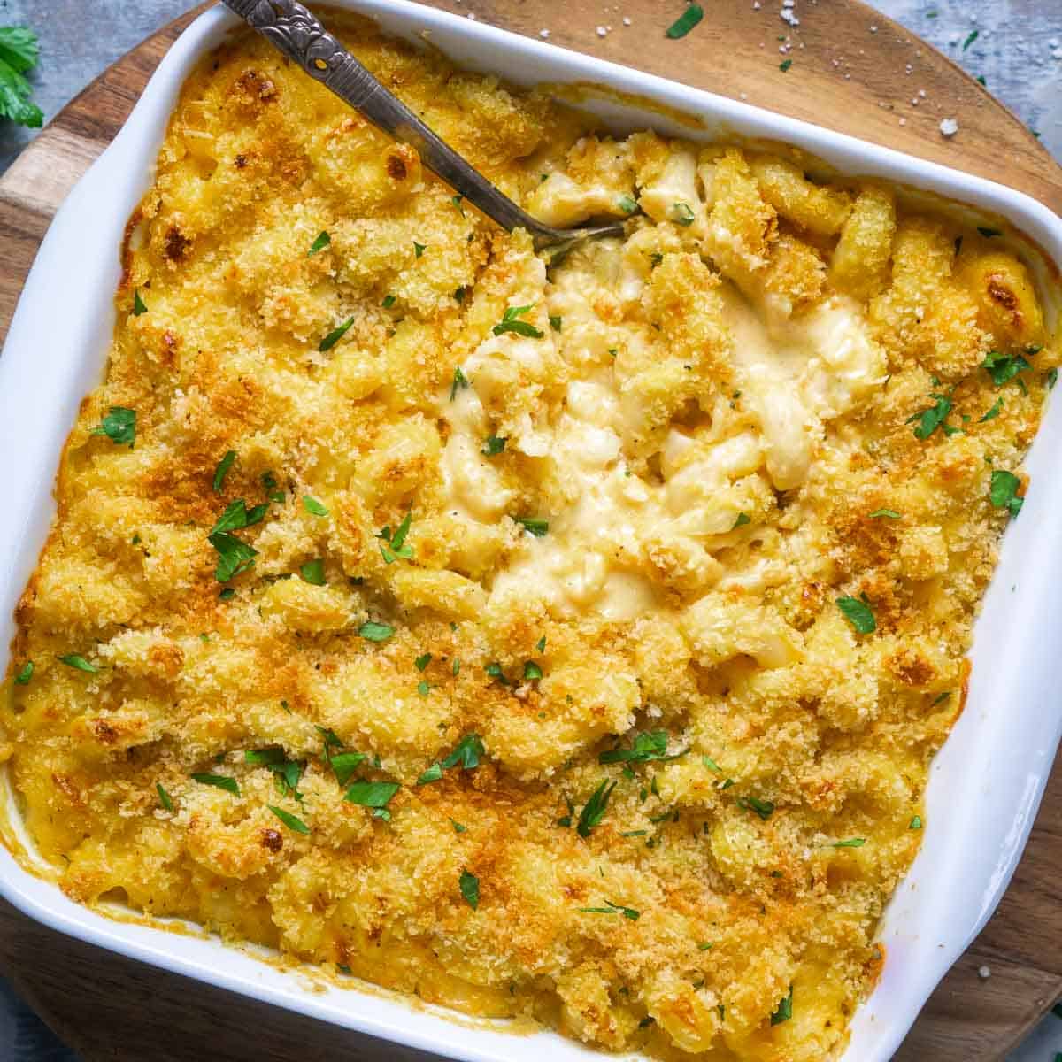 baked butternut squash mac and cheese with crispy panko topping in white baking dish with serving spoon