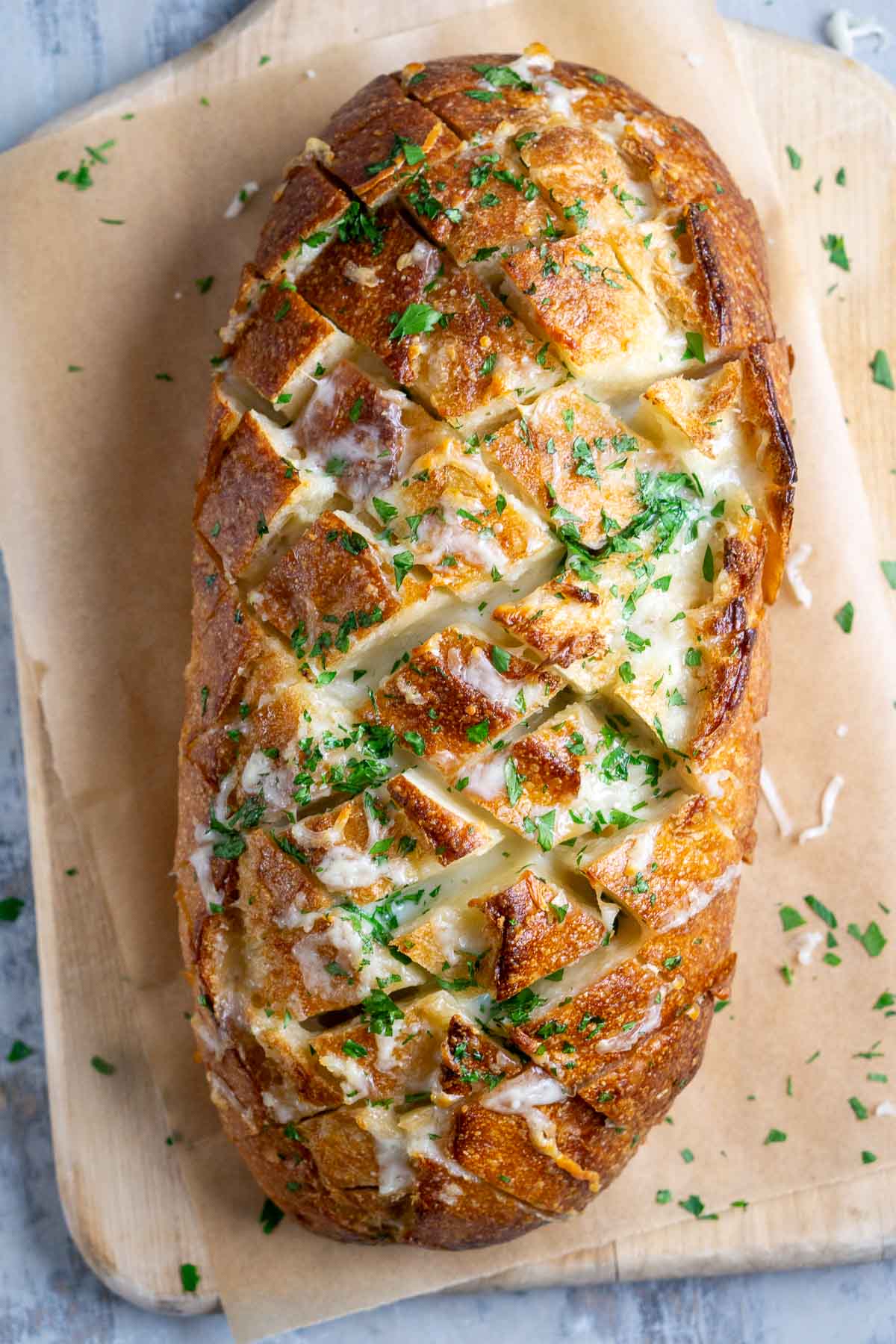 baked cheesy pull apart bread on parchment-lined cutting board ready to serve
