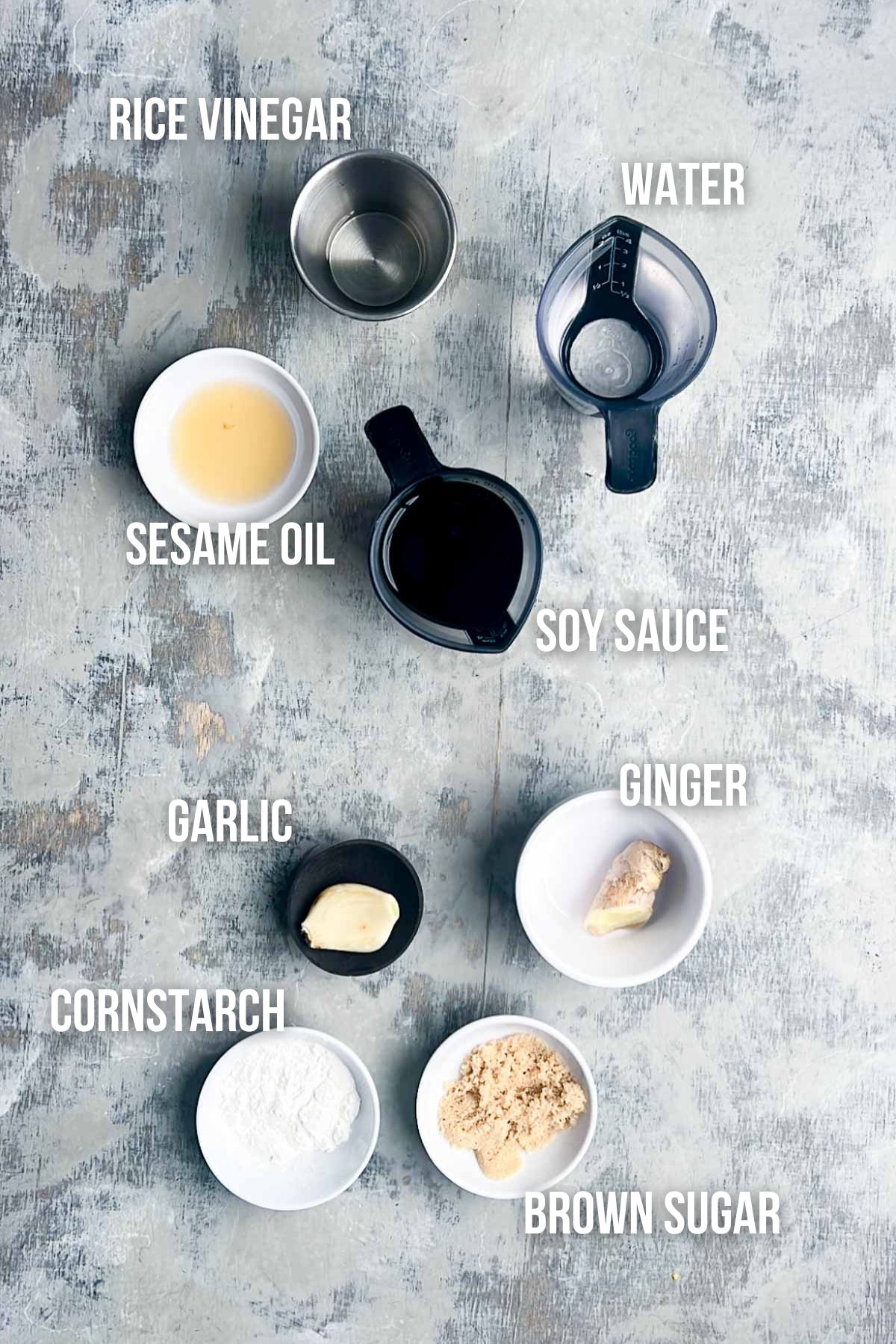 Eight labeled bowls and cups containing rice vinegar, water, sesame oil, soy sauce, garlic, ginger, cornstarch, and brown sugar&mdash;ingredients needed to make flavorful chicken lettuce wraps.