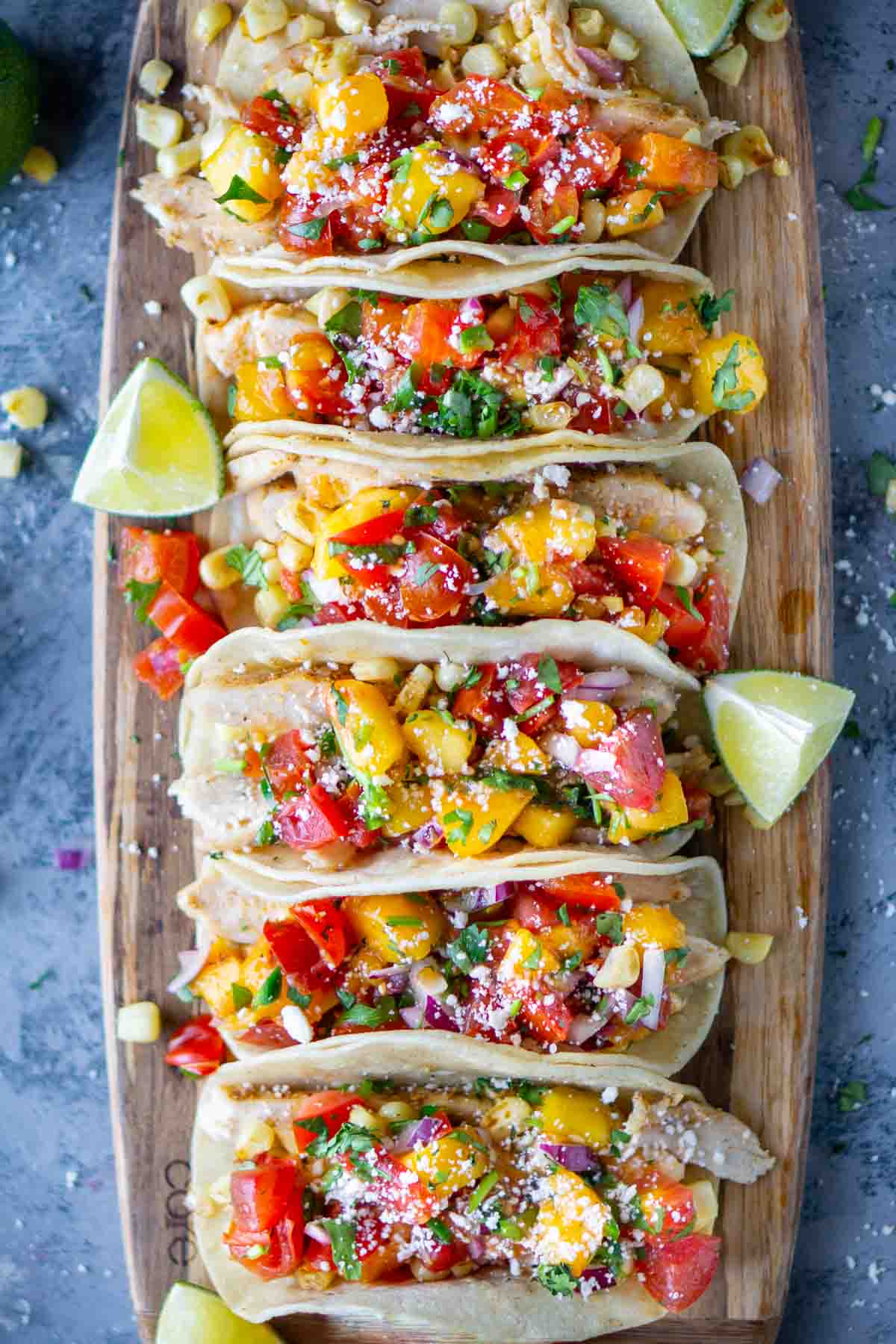 chicken street tacos on wood serving board garnished with lime wedges