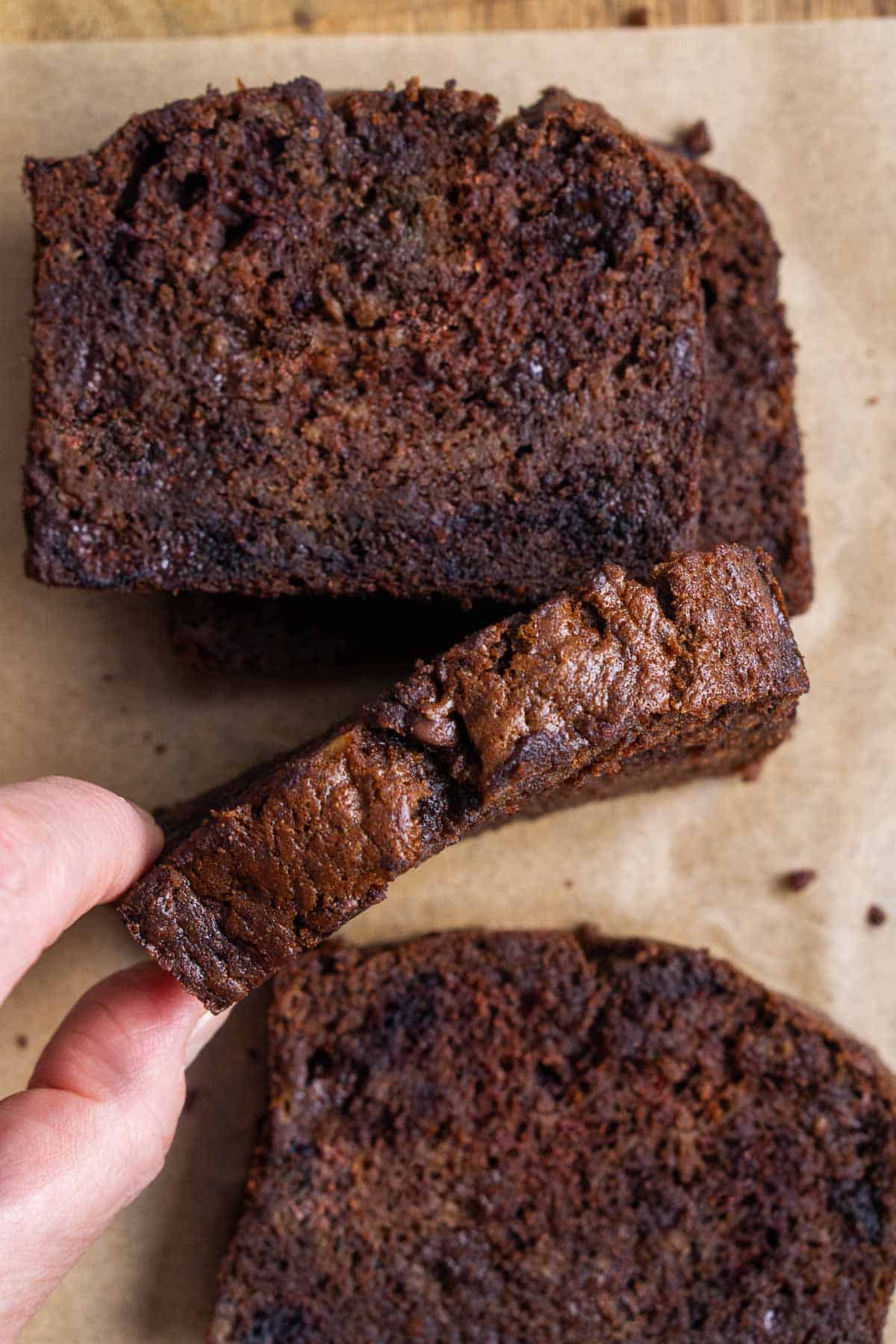 person's hand grabs a slice of chocolate banana bread