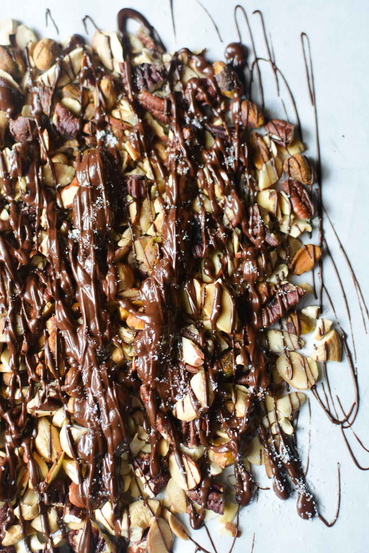 Chocolate drizzled mixed nuts on parchment paper