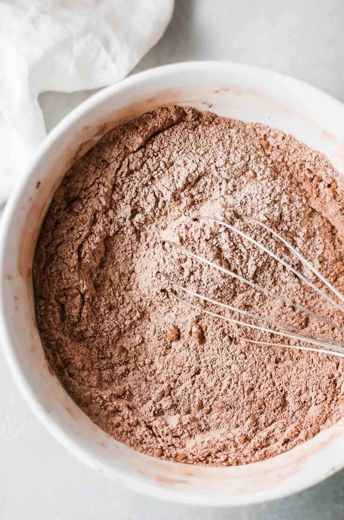 dry chocolate pancake ingredients in white bowl with whisk