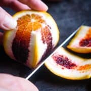 peel is being removed from blood orange with chef's knife