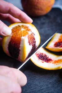 peel is being removed from blood orange with chef's knife