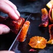 blood orange is being sliced with chef's knfe